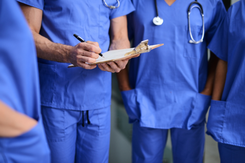 Image of doctors in scrubs gathered around a clipboard | Confidential Waste disposal in the healthcare industry