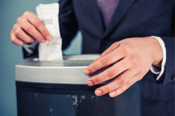Image of a man using a paper shredder to shred a receipt confidential waste disposal